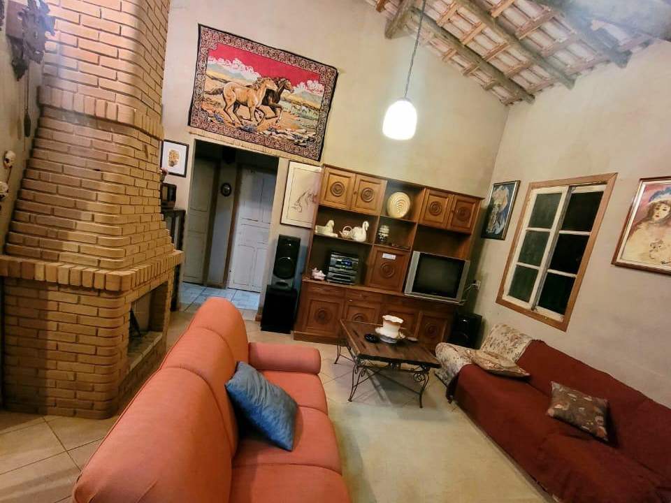 A sala de estar com a lareira de tijolo aparente, pé-direito alto e telha à vista.